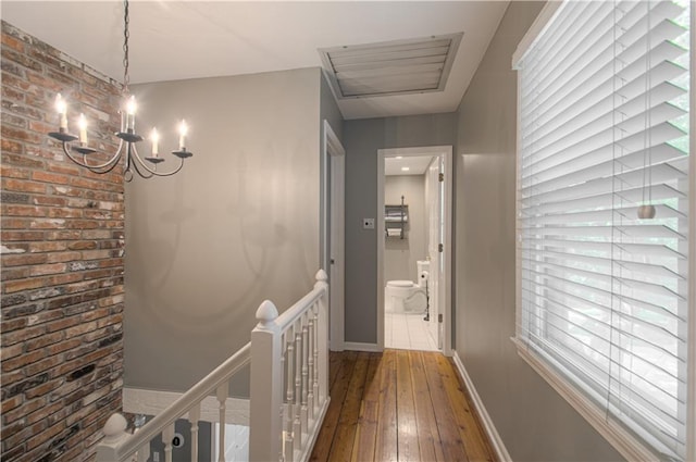 601 NW 41st St, Kansas City, MO 64116 - corridor with an upstairs landing, brick wall, hardwood / wood-style flooring, a chandelier, and baseboards
