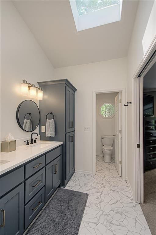 601 NW 41st St, Kansas City, MO 64116 - full bathroom featuring a skylight, marble finish flooring, vaulted ceiling, double vanity, and toilet