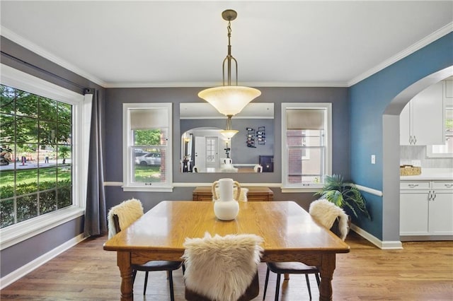 440 E 74th Ter, Kansas City, MO 64131 - dining room featuring arched walkways, light wood-style floors, healthy amount of natural light, baseboards, and ornamental molding