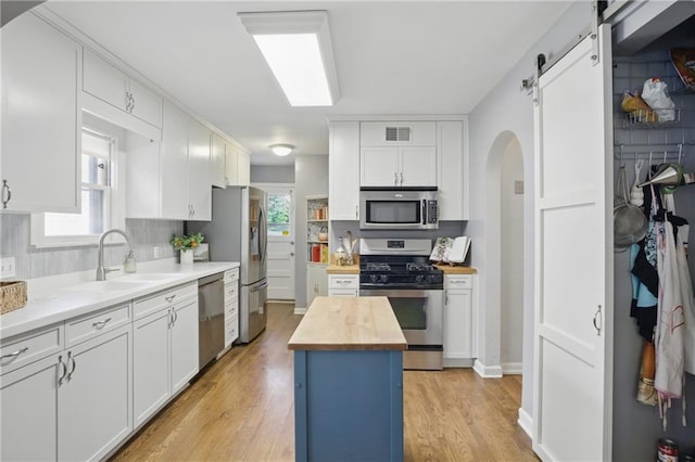 440 E 74th Ter, Kansas City, MO 64131 - kitchen featuring wood counters, stainless steel appliances, a sink, arched walkways, and light wood finished floors