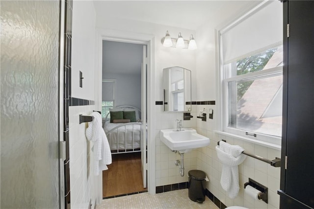 440 E 74th Ter, Kansas City, MO 64131 - ensuite bathroom with tile walls, a stall shower, tile patterned flooring, and wainscoting