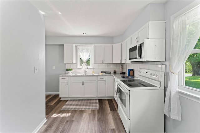 2204 S Cedar Ave, Independence, MO 64052 - kitchen featuring white appliances, dark wood finished floors, backsplash, white cabinets, and baseboards