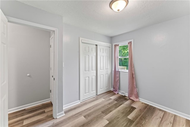 2204 S Cedar Ave, Independence, MO 64052 - unfurnished bedroom with a textured ceiling, wood finished floors, a closet, and baseboards