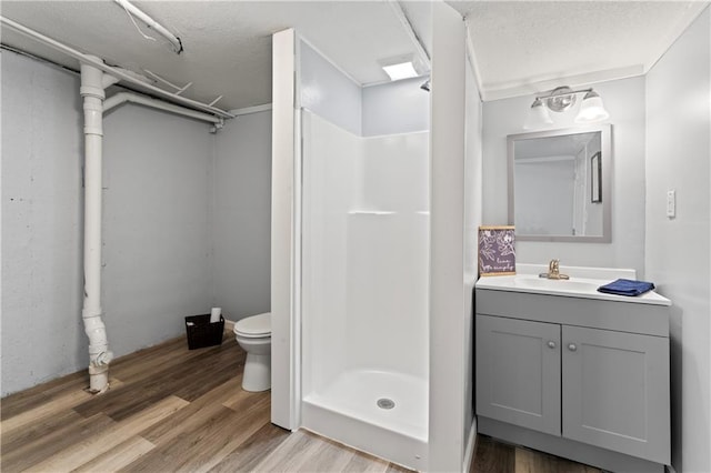 2204 S Cedar Ave, Independence, MO 64052 - bathroom featuring a stall shower, toilet, vanity, wood finished floors, and a textured ceiling