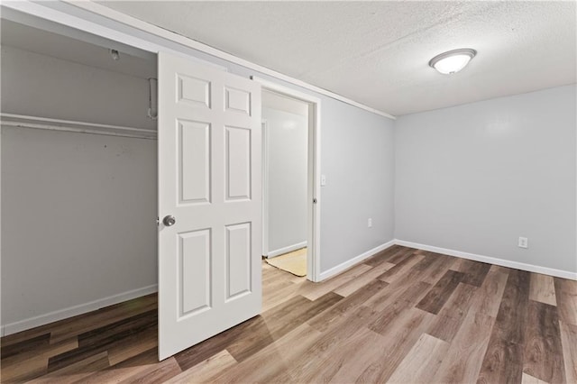 2204 S Cedar Ave, Independence, MO 64052 - unfurnished bedroom with a textured ceiling, wood finished floors, baseboards, and a closet