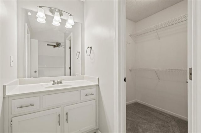 10118 E 220th St, Peculiar, MO 64078 - bathroom with vanity, a spacious closet, a ceiling fan, a textured ceiling, and baseboards