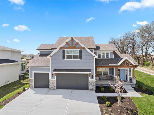 8009 Round Prairie St, Shawnee, KS 66220 - view of front facade featuring stone siding, a shingled roof, concrete driveway, covered porch, and a garage