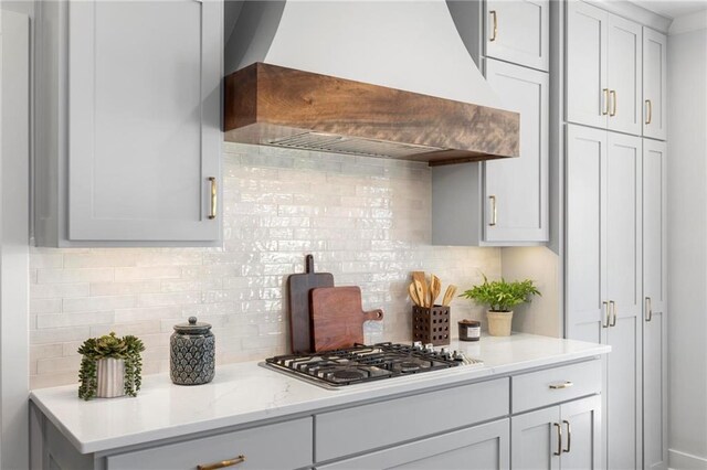 8009 Round Prairie St, Shawnee, KS 66220 - kitchen with premium range hood, stainless steel gas cooktop, decorative backsplash, and light stone counters