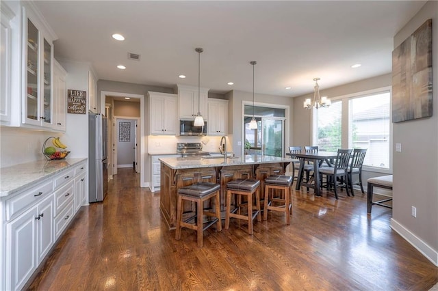 17304 S Schweiger Dr, Olathe, KS 66062 - kitchen with appliances with stainless steel finishes, white cabinets, a kitchen bar, a chandelier, and a sink
