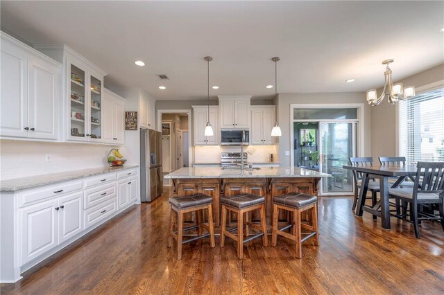 17304 S Schweiger Dr, Olathe, KS 66062 - kitchen with stainless steel appliances, white cabinetry, a chandelier, a breakfast bar, and dark wood-type flooring
