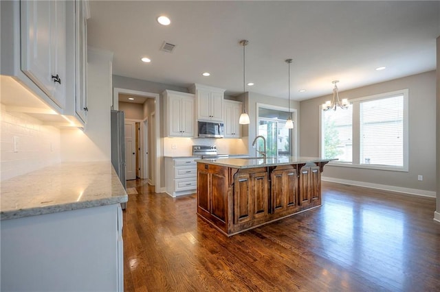 17304 S Schweiger Dr, Olathe, KS 66062 - kitchen featuring stainless steel appliances, a chandelier, tasteful backsplash, dark wood finished floors, and white cabinets