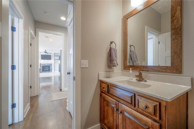 17304 S Schweiger Dr, Olathe, KS 66062 - bathroom featuring vanity, wood finished floors, recessed lighting, ceiling fan, and a glass covered fireplace