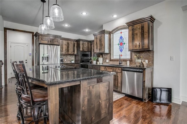 17224 Haskins St, Overland Park, KS 66062 - kitchen with appliances with stainless steel finishes, dark wood-style floors, a kitchen bar, a kitchen island, and tasteful backsplash