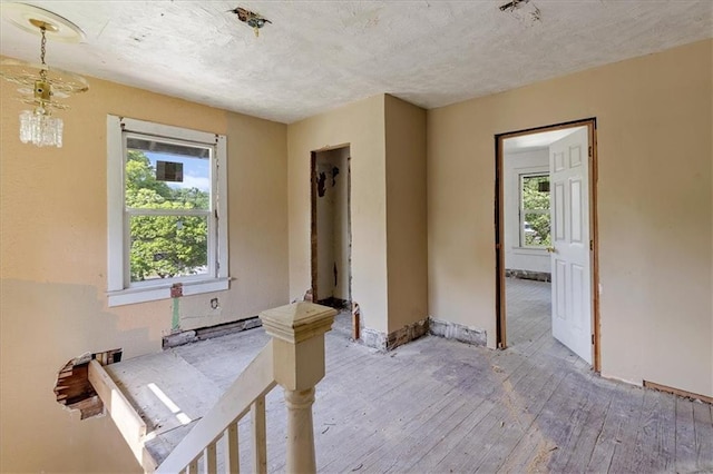 2921 E 54th St, Kansas City, MO 64130 - empty room with light wood-type flooring, plenty of natural light, a textured ceiling, and baseboards