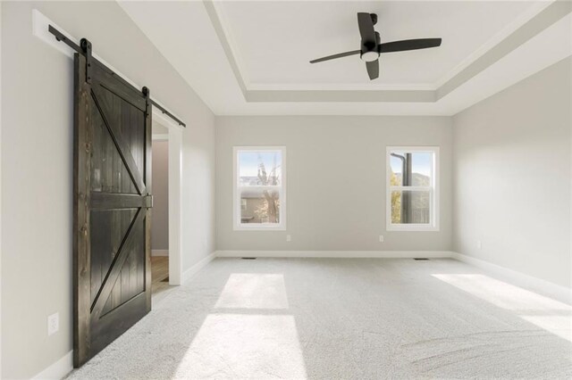 3116 SW Summit View Trl, Lees Summit, MO 64082 - unfurnished bedroom featuring a barn door, a tray ceiling, light carpet, and baseboards