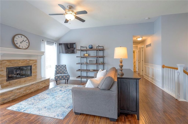 23600 W 59th St, Shawnee, KS 66226 - living area featuring a ceiling fan, wood finished floors, vaulted ceiling, a stone fireplace, and a wainscoted wall