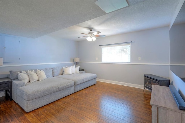 23600 W 59th St, Shawnee, KS 66226 - living room with a wood stove, wood-type flooring, ceiling fan, a textured ceiling, and baseboards