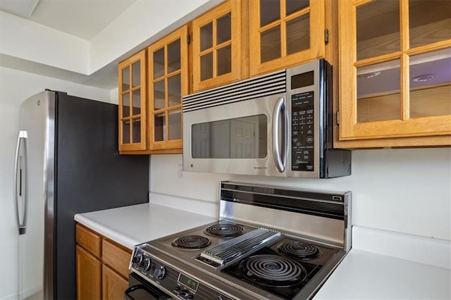 1145 Camp Branch Rd, Sunrise Beach, MO 65079 - kitchen featuring stainless steel appliances, light countertops, glass insert cabinets, and brown cabinetry