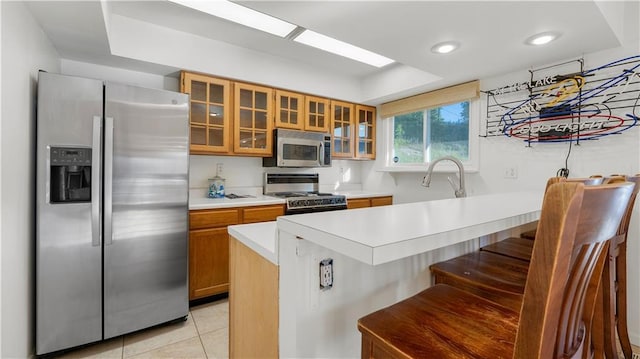 1145 Camp Branch Rd, Sunrise Beach, MO 65079 - kitchen with stainless steel appliances, brown cabinets, light countertops, a peninsula, and a breakfast bar