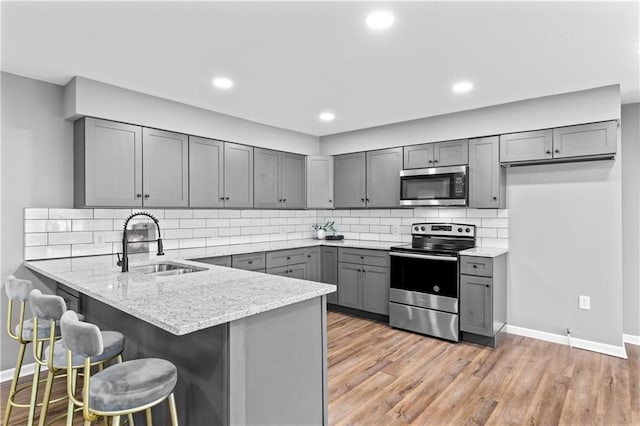 2081 Willow Ln, Excelsior Springs, MO 64024 - kitchen with appliances with stainless steel finishes, gray cabinetry, a sink, a peninsula, and baseboards