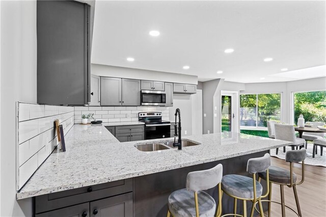 2081 Willow Ln, Excelsior Springs, MO 64024 - kitchen with appliances with stainless steel finishes, a sink, light stone counters, gray cabinetry, and a peninsula