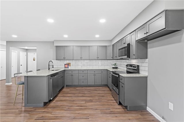 2081 Willow Ln, Excelsior Springs, MO 64024 - kitchen with gray cabinets, stainless steel appliances, a sink, a peninsula, and a kitchen breakfast bar