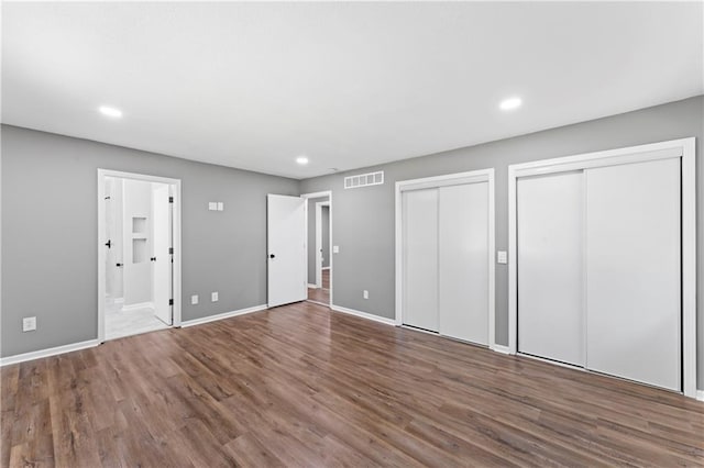 2081 Willow Ln, Excelsior Springs, MO 64024 - unfurnished bedroom with multiple closets, wood finished floors, baseboards, recessed lighting, and ensuite bath