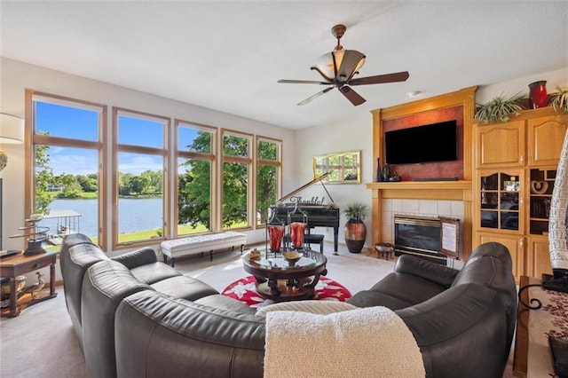 15471 Cedar Ln, Basehor, KS 66007 - carpeted living room featuring a tiled fireplace, a ceiling fan, and a water view