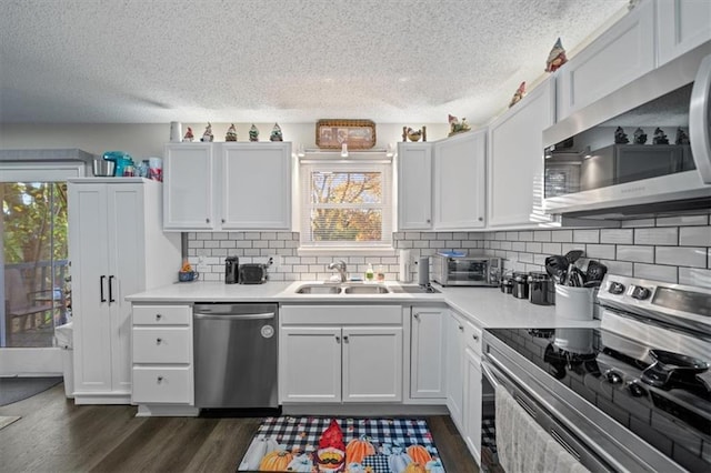 3620 S Northern Blvd, Independence, MO 64052 - kitchen with appliances with stainless steel finishes, a sink, healthy amount of natural light, dark wood-type flooring, and a textured ceiling