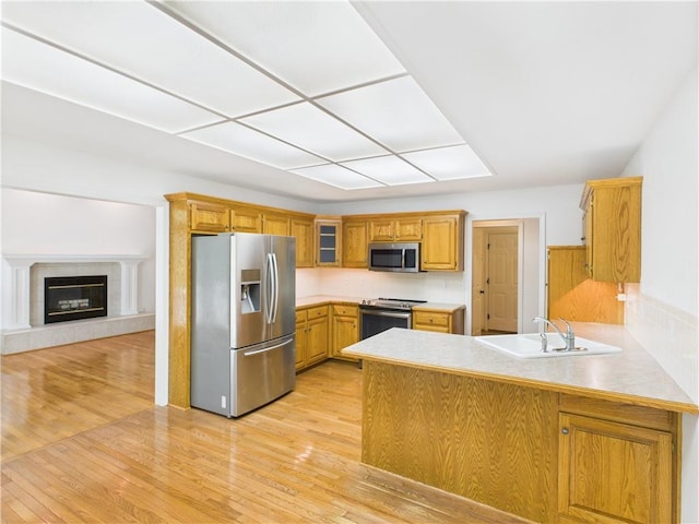 503 Quail Trl, Warrensburg, MO 64093 - kitchen with appliances with stainless steel finishes, a peninsula, light wood finished floors, glass insert cabinets, and light countertops