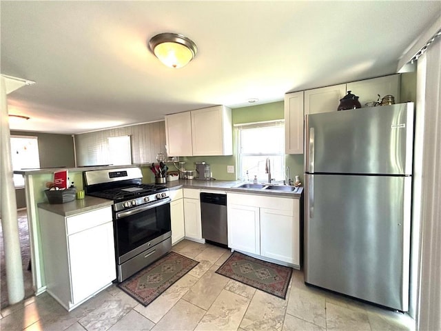 3408 67th St, Kansas City, MO 64119 - kitchen featuring stainless steel appliances, a sink, a peninsula, and white cabinetry