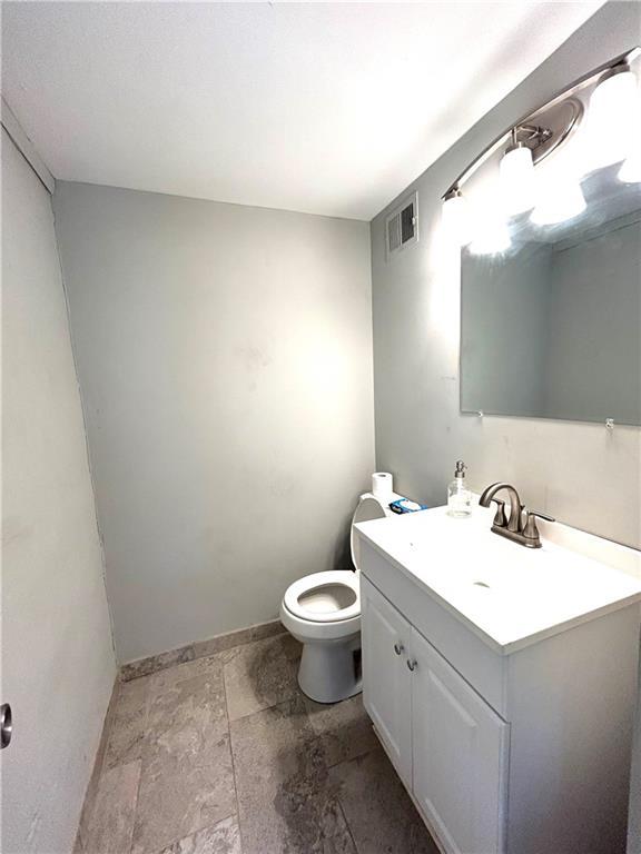 3408 67th St, Kansas City, MO 64119 - bathroom with baseboards, vanity, toilet, and stone finish flooring