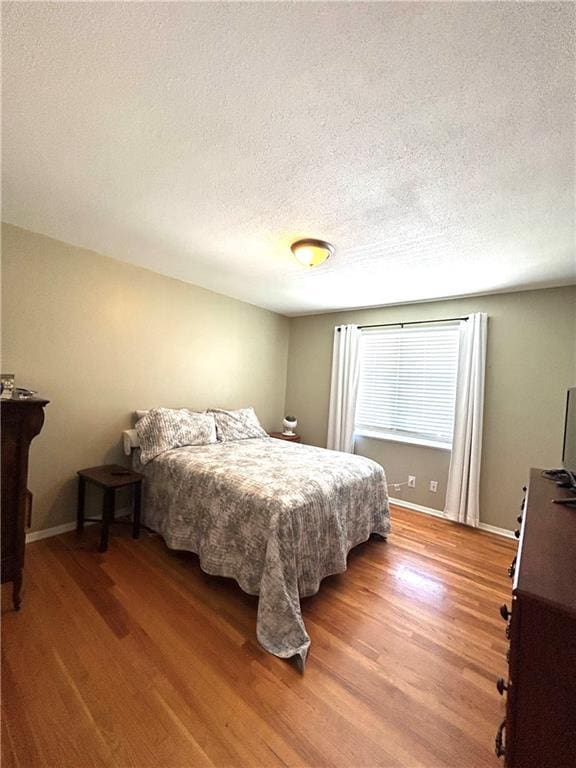 3408 67th St, Kansas City, MO 64119 - bedroom featuring light wood finished floors, a textured ceiling, and baseboards