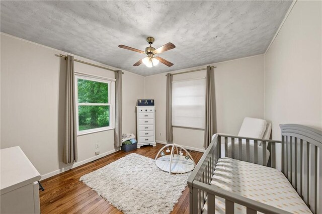 2912 W 75th St, Prairie Village, KS 66208 - bedroom with wood finished floors, a textured ceiling, a crib, and a ceiling fan