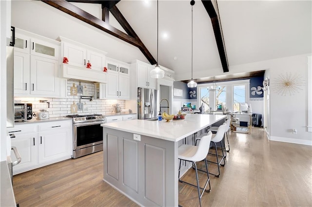 905 SE Wood Ridge Ct, Blue Springs, MO 64014 - kitchen featuring stainless steel appliances, tasteful backsplash, light countertops, beamed ceiling, and a center island with sink