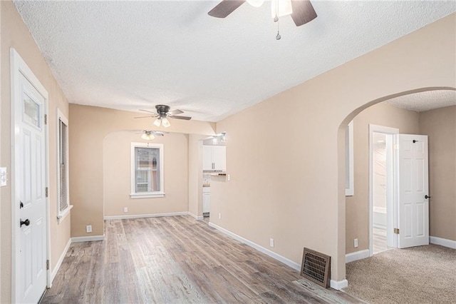 4224 Monroe Ave, Kansas City, MO 64130 - unfurnished room with ceiling fan, arched walkways, a textured ceiling, light wood-type flooring, and baseboards