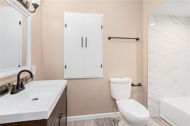 4224 Monroe Ave, Kansas City, MO 64130 - bathroom featuring toilet, vanity, baseboards, and wood finished floors