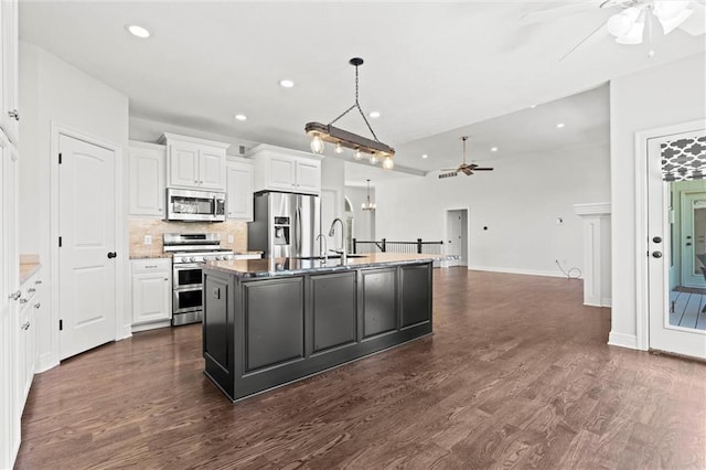 17105 Bo Cir, Tonganoxie, KS 66086 - kitchen featuring appliances with stainless steel finishes, ceiling fan, white cabinets, a kitchen island with sink, and backsplash