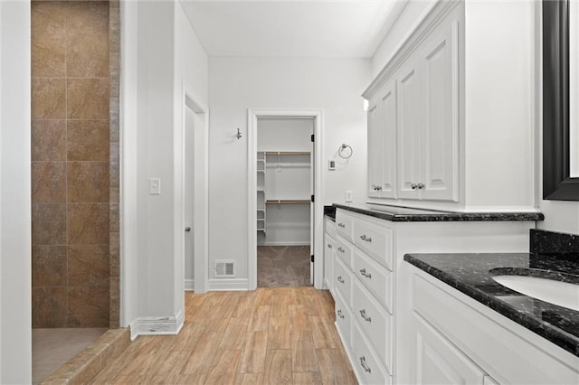 17105 Bo Cir, Tonganoxie, KS 66086 - bathroom with vanity, a walk in closet, wood finished floors, a tile shower, and baseboards