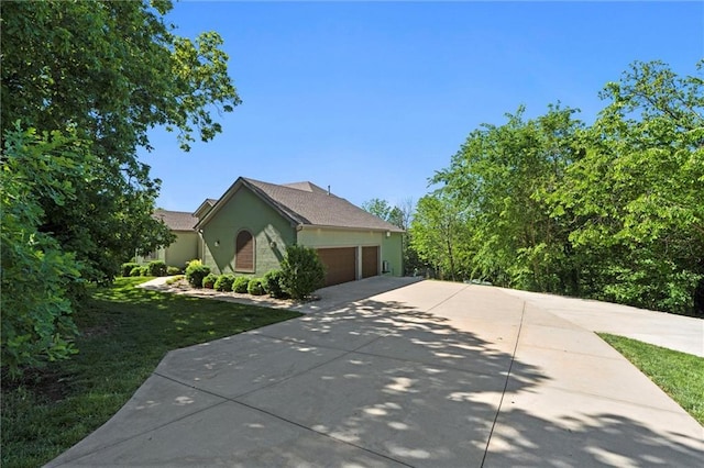 17105 Bo Cir, Tonganoxie, KS 66086 - view of side of property featuring concrete driveway, a garage, a lawn, and stucco siding