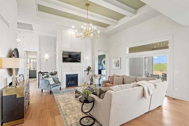 8013 Payne St, Shawnee, KS 66220 - living room featuring a high ceiling, a chandelier, light wood-style floors, a fireplace, and beamed ceiling