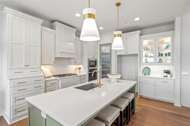8013 Payne St, Shawnee, KS 66220 - kitchen with a sink, stainless steel appliances, light wood finished floors, white cabinets, and an island with sink