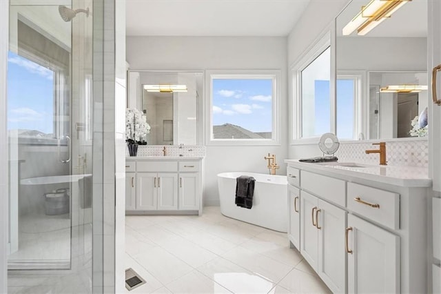 8013 Payne St, Shawnee, KS 66220 - full bathroom with two vanities, a shower stall, a freestanding bath, tasteful backsplash, and tile patterned flooring