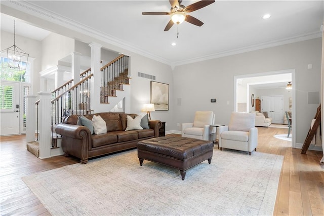 15618 Meadowbrook Ct, Raymore, MO 64083 - living area with stairway, a ceiling fan, light wood finished floors, ornamental molding, and a chandelier