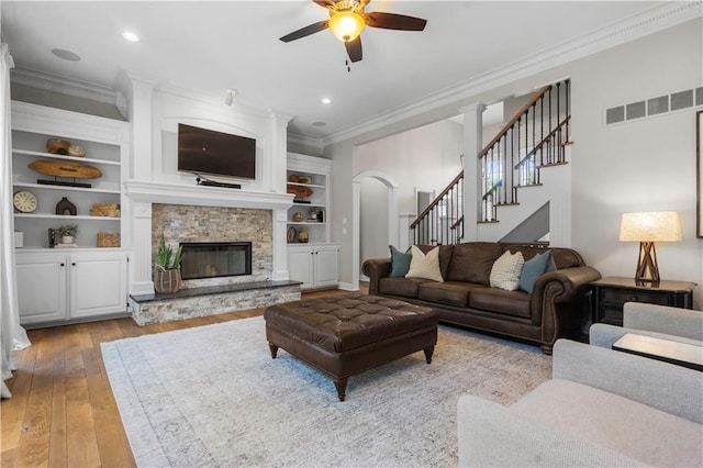 15618 Meadowbrook Ct, Raymore, MO 64083 - living area with crown molding, a ceiling fan, light wood-style flooring, stairs, and arched walkways
