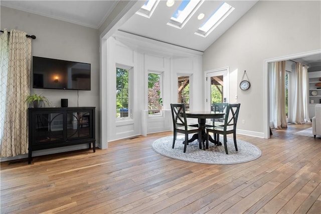 15618 Meadowbrook Ct, Raymore, MO 64083 - dining room featuring plenty of natural light, light wood finished floors, a skylight, high vaulted ceiling, and ornamental molding