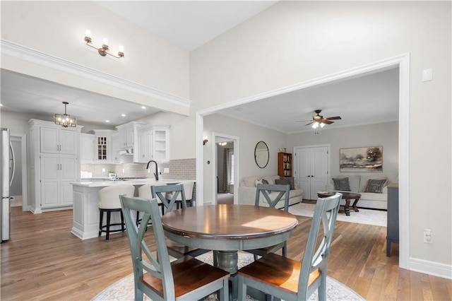 15618 Meadowbrook Ct, Raymore, MO 64083 - dining area featuring light wood-style floors, ceiling fan, a chandelier, and baseboards
