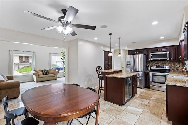 14401 Craig Ave, Grandview, MO 64030 - kitchen with appliances with stainless steel finishes, a sink, dark brown cabinetry, tasteful backsplash, and a center island