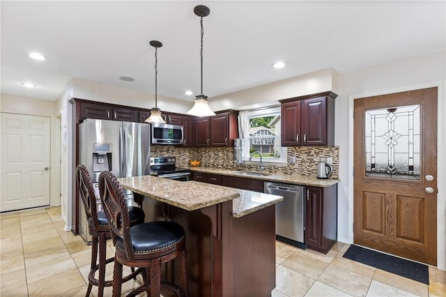14401 Craig Ave, Grandview, MO 64030 - kitchen featuring appliances with stainless steel finishes, a sink, tasteful backsplash, a kitchen island, and decorative light fixtures