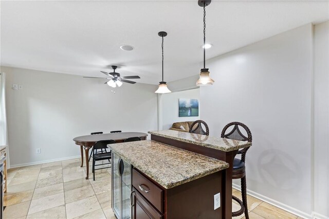 14401 Craig Ave, Grandview, MO 64030 - kitchen featuring a breakfast bar area, pendant lighting, dark brown cabinets, a ceiling fan, and a center island
